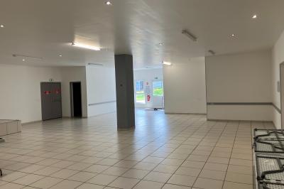 Plan d’un bâtiment avec disposition des pièces, entrées, parking et espaces extérieurs indiqués.