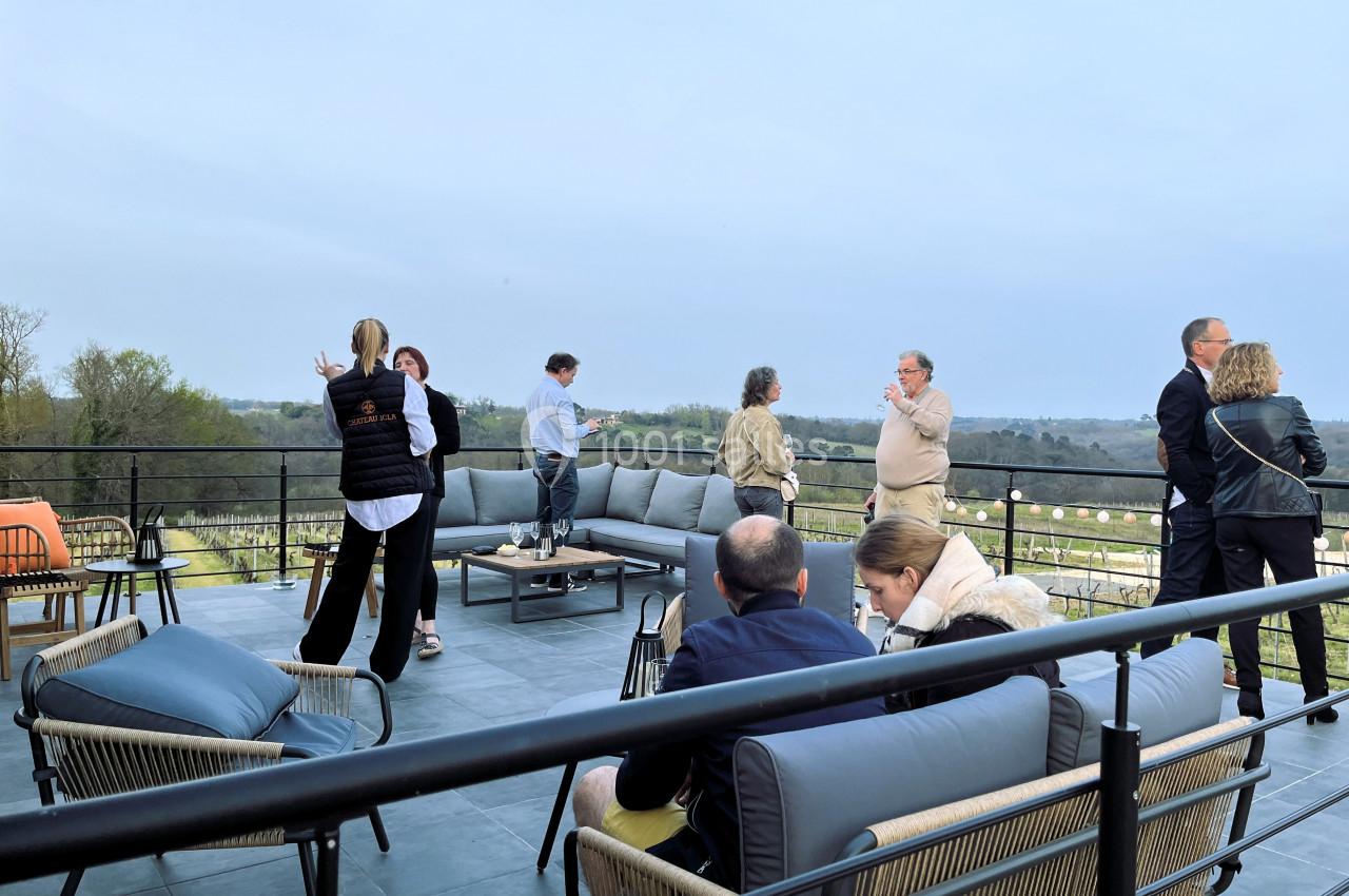 Personnes discutant sur une terrasse aménagée avec vue sur un paysage rural au crépuscule.