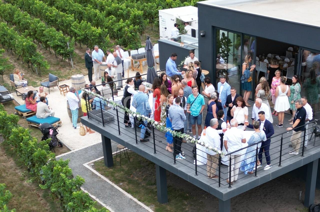 Groupe de personnes réunies sur une terrasse moderne surplombant des vignes, lors d'un événement en plein air.