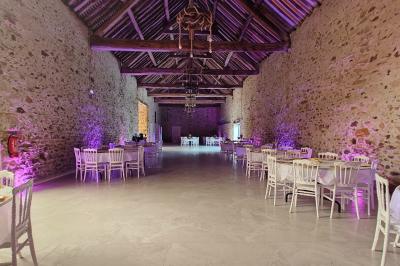 Allée décorée de fleurs blanches dans une salle en pierre éclairée par des guirlandes lumineuses.