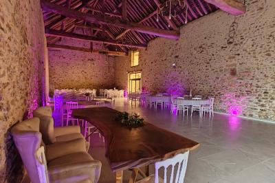 Allée décorée de fleurs blanches dans une salle en pierre éclairée par des guirlandes lumineuses.