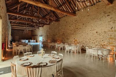 Allée décorée de fleurs blanches dans une salle en pierre éclairée par des guirlandes lumineuses.