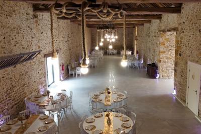 Allée décorée de fleurs blanches dans une salle en pierre éclairée par des guirlandes lumineuses.