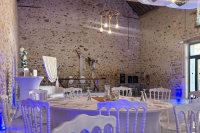Allée décorée de fleurs blanches dans une salle en pierre éclairée par des guirlandes lumineuses.