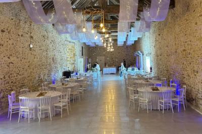 Allée décorée de fleurs blanches dans une salle en pierre éclairée par des guirlandes lumineuses.