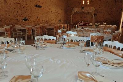 Allée décorée de fleurs blanches dans une salle en pierre éclairée par des guirlandes lumineuses.