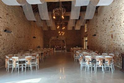 Allée décorée de fleurs blanches dans une salle en pierre éclairée par des guirlandes lumineuses.