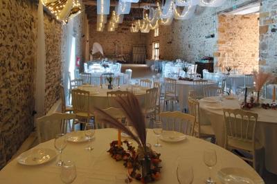 Allée décorée de fleurs blanches dans une salle en pierre éclairée par des guirlandes lumineuses.