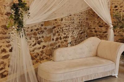 Allée décorée de fleurs blanches dans une salle en pierre éclairée par des guirlandes lumineuses.