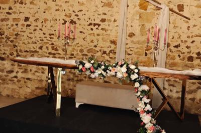Allée décorée de fleurs blanches dans une salle en pierre éclairée par des guirlandes lumineuses.