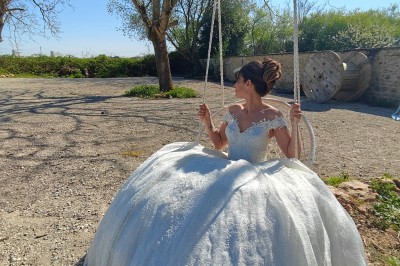 Allée décorée de fleurs blanches dans une salle en pierre éclairée par des guirlandes lumineuses.