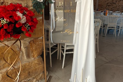 Allée décorée de fleurs blanches dans une salle en pierre éclairée par des guirlandes lumineuses.