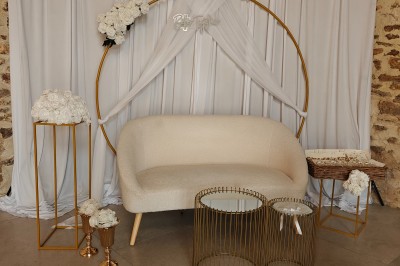 Allée décorée de fleurs blanches dans une salle en pierre éclairée par des guirlandes lumineuses.