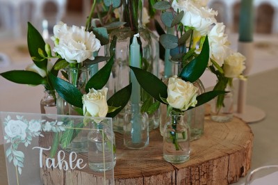 Allée décorée de fleurs blanches dans une salle en pierre éclairée par des guirlandes lumineuses.