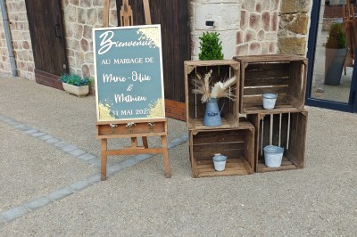 Allée décorée de fleurs blanches dans une salle en pierre éclairée par des guirlandes lumineuses.