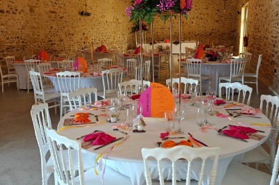 Allée décorée de fleurs blanches dans une salle en pierre éclairée par des guirlandes lumineuses.