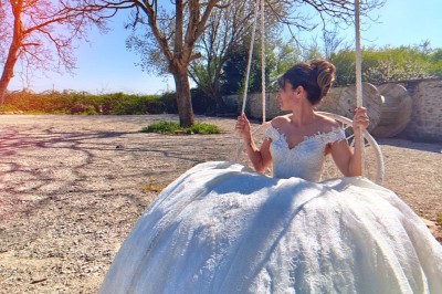Allée décorée de fleurs blanches dans une salle en pierre éclairée par des guirlandes lumineuses.