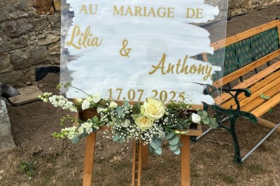 Allée décorée de fleurs blanches dans une salle en pierre éclairée par des guirlandes lumineuses.
