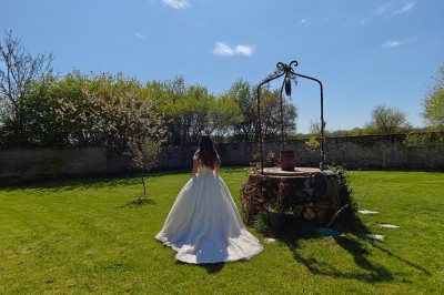 Allée décorée de fleurs blanches dans une salle en pierre éclairée par des guirlandes lumineuses.
