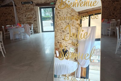 Allée décorée de fleurs blanches dans une salle en pierre éclairée par des guirlandes lumineuses.
