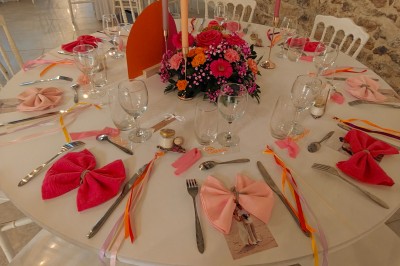 Allée décorée de fleurs blanches dans une salle en pierre éclairée par des guirlandes lumineuses.