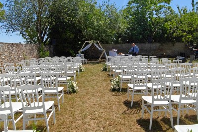 Allée décorée de fleurs blanches dans une salle en pierre éclairée par des guirlandes lumineuses.
