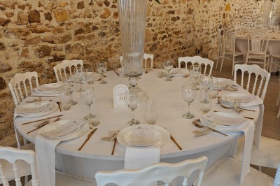 Allée décorée de fleurs blanches dans une salle en pierre éclairée par des guirlandes lumineuses.