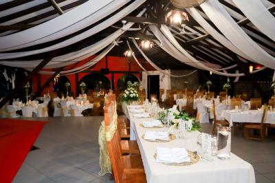 Grande terrasse couverte avec structure en bois, sol carrelé et quelques tables et chaises disposées près des ouvertures.