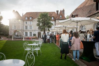 Des convives discutent près d'un barbecue en plein air, sous des parasols éclairés, dans une ambiance nocturne festive.