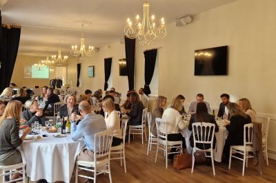 Des convives discutent près d'un barbecue en plein air, sous des parasols éclairés, dans une ambiance nocturne festive.
