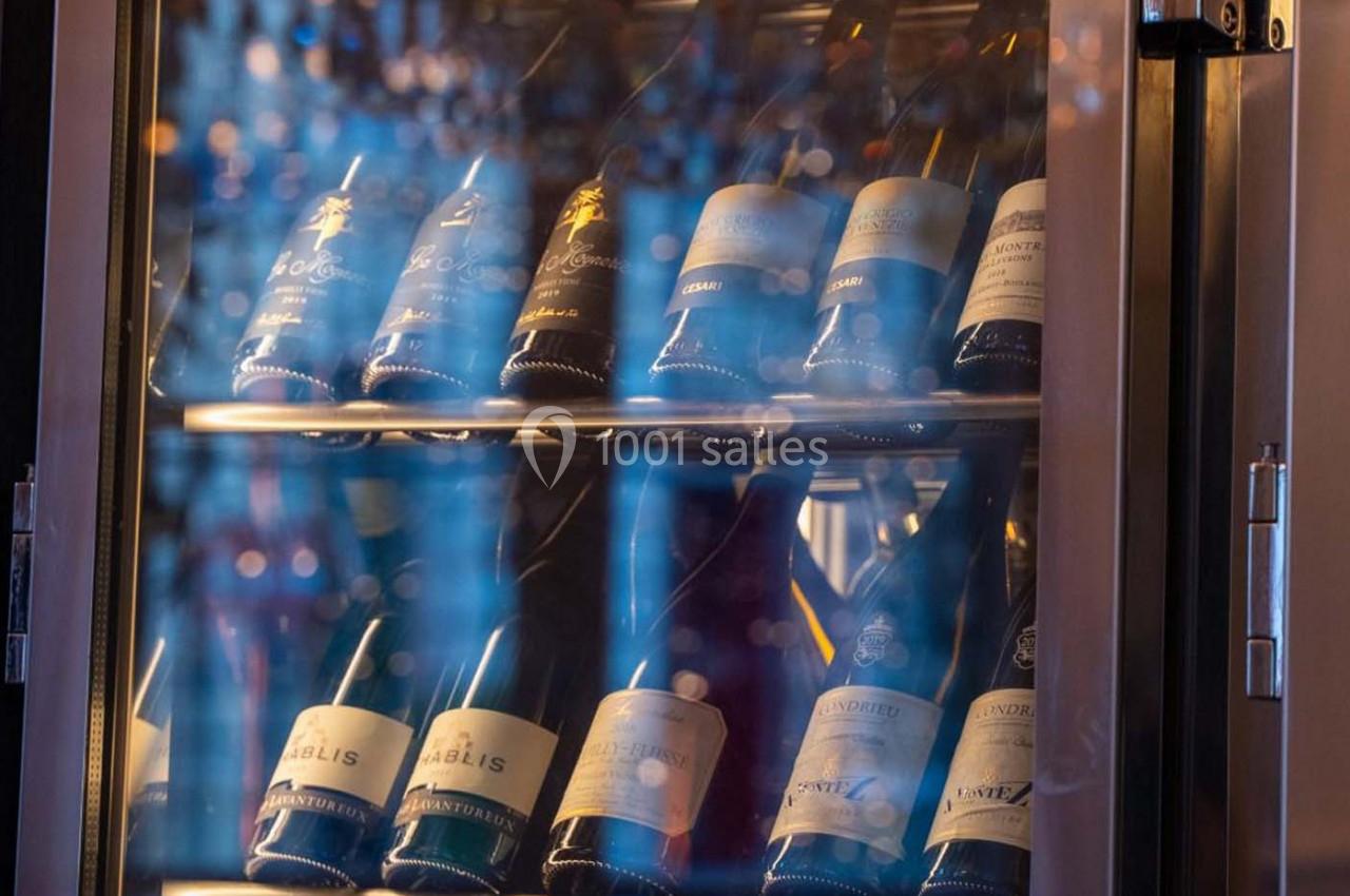 Bouteilles de vin blanc et rouge rangées sur des étagères dans une cave à vin réfrigérée.