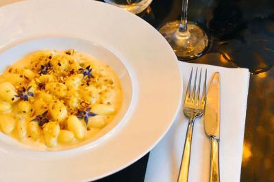 Plat italien gratiné avec sauce tomate, fromage fondu et feuilles de basilic, présenté dans un plat noir.