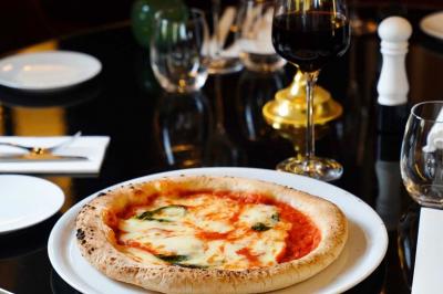 Plat italien gratiné avec sauce tomate, fromage fondu et feuilles de basilic, présenté dans un plat noir.