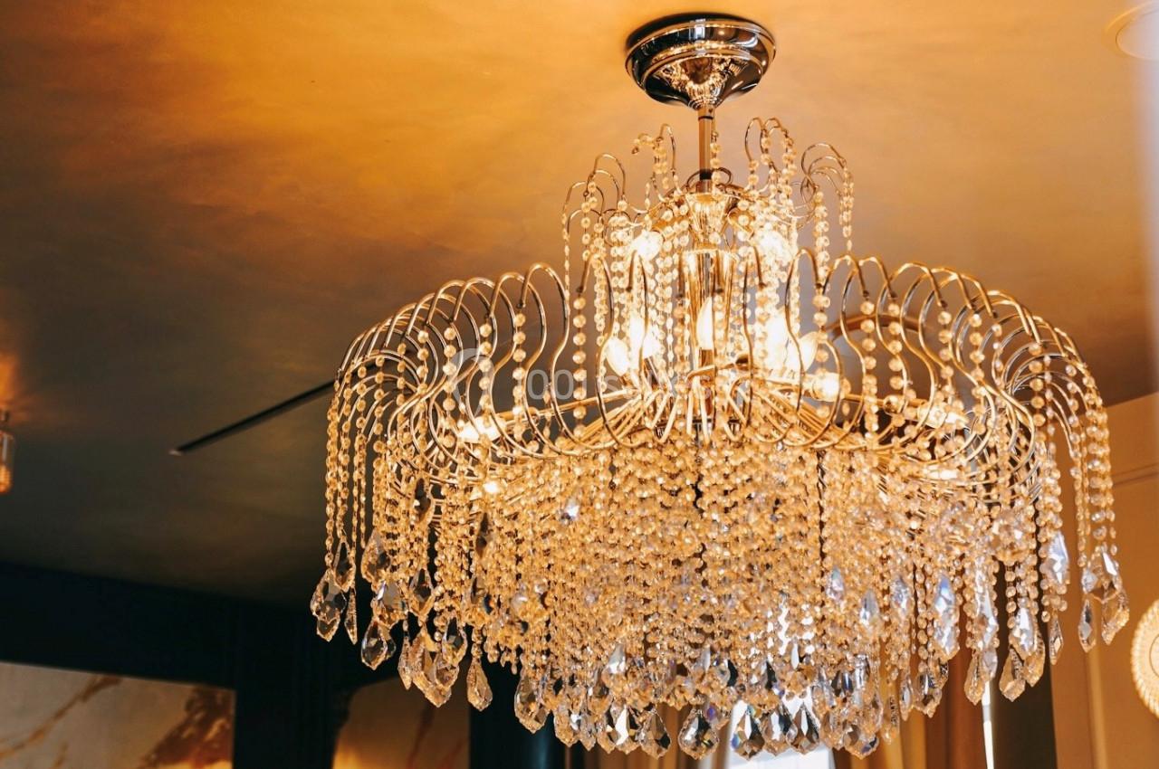 Lustre en cristal suspendu, illuminé, avec des détails étincelants dans un intérieur au plafond doré.