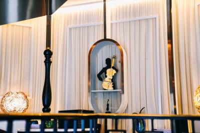 Un comptoir décoratif avec des objets design, éclairé par une lumière chaleureuse et entouré de rideaux blancs.