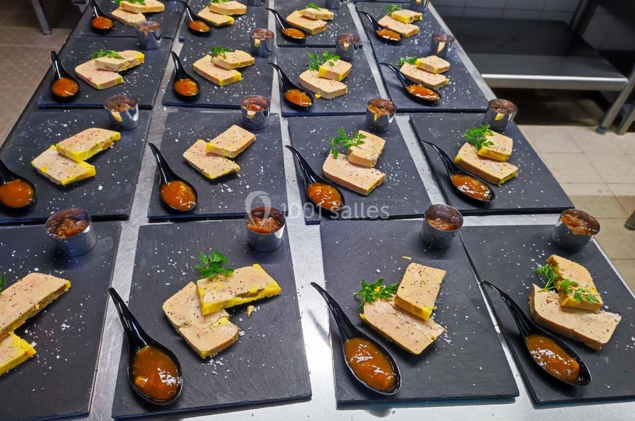 Assiettes de foie gras avec chutney, servies sur des ardoises noires, disposées en rangées dans une cuisine.