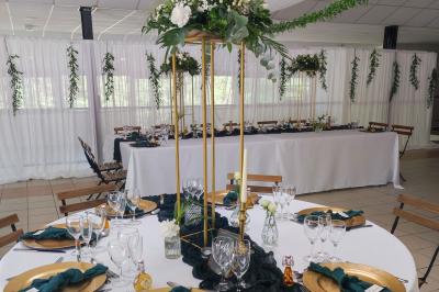 Ardoise décorative accrochée à une grille en fer forgé, entourée de végétation et d'un voile blanc.