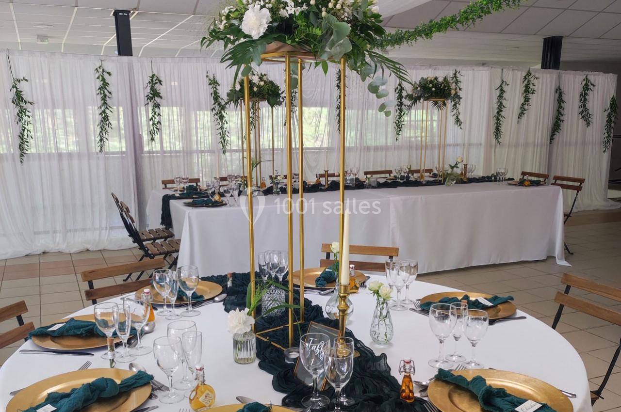 Table décorée pour un événement avec vaisselle élégante, serviettes vertes, centres de table floraux et arrière-plan…