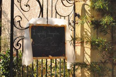 Ardoise décorative accrochée à une grille en fer forgé, entourée de végétation et d'un voile blanc.