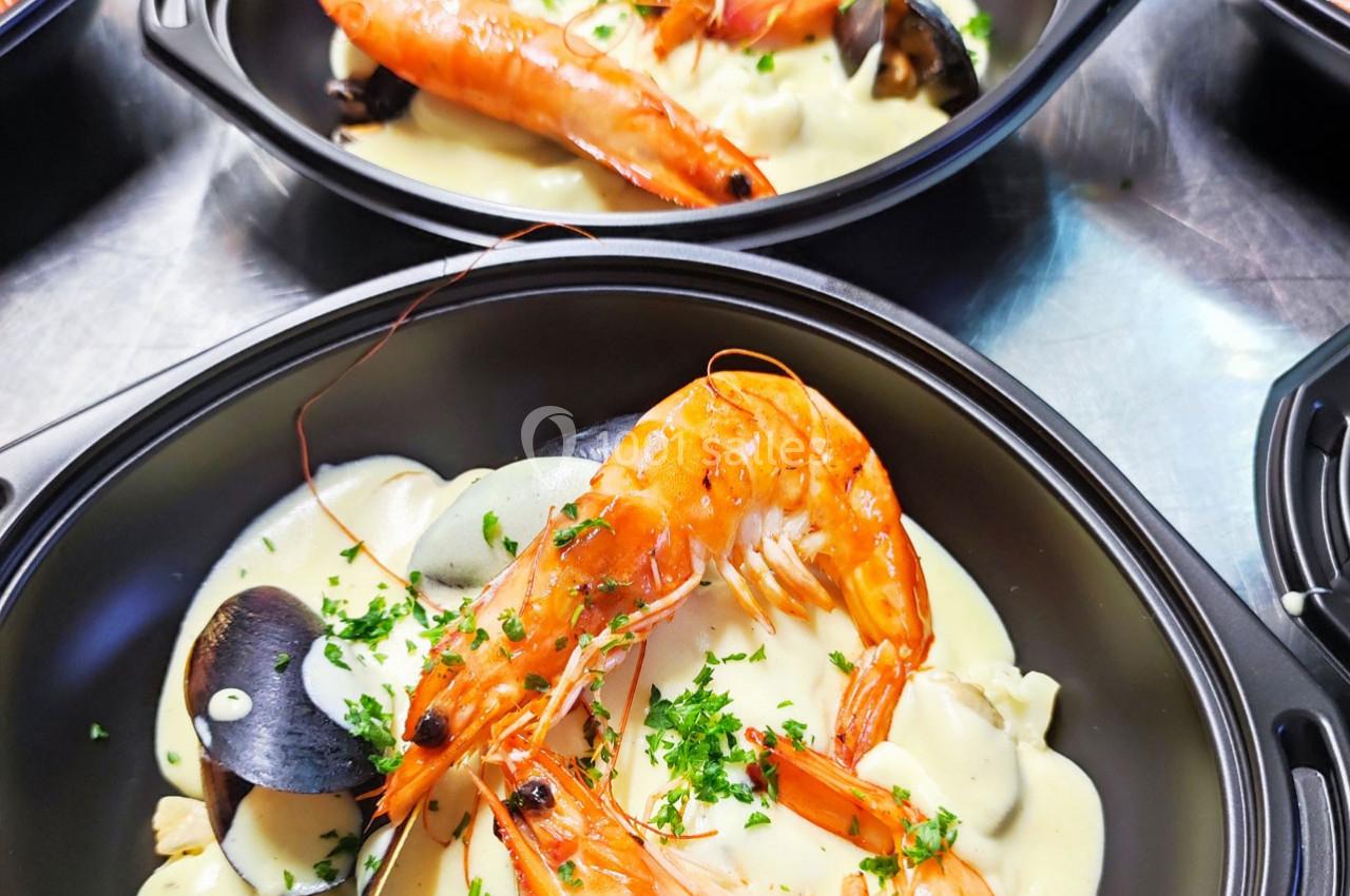 Assiette de fruits de mer avec crevettes, moules et sauce crémeuse, garnie de persil frais.