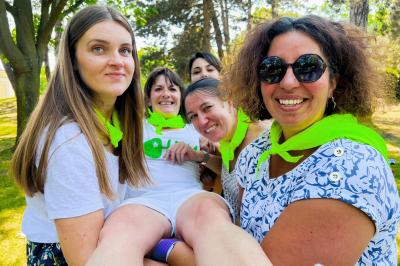 Une personne en combinaison rouge se tient devant un groupe d'adultes et d'enfants sur une aire extérieure.