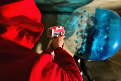 Une personne en combinaison rouge se tient devant un groupe d'adultes et d'enfants sur une aire extérieure.