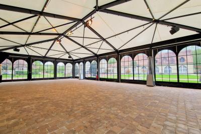 Salle spacieuse avec canapés, baby-foot, table de jeux et grandes fenêtres donnant sur un extérieur arboré.