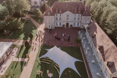 Salle spacieuse avec canapés, baby-foot, table de jeux et grandes fenêtres donnant sur un extérieur arboré.