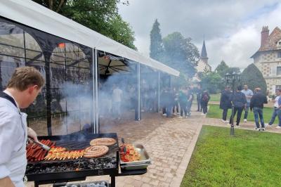 Salle spacieuse avec canapés, baby-foot, table de jeux et grandes fenêtres donnant sur un extérieur arboré.