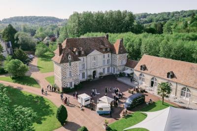 Salle spacieuse avec canapés, baby-foot, table de jeux et grandes fenêtres donnant sur un extérieur arboré.