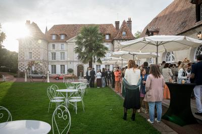Salle spacieuse avec canapés, baby-foot, table de jeux et grandes fenêtres donnant sur un extérieur arboré.