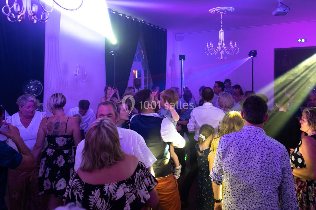 Groupe de personnes dansant et discutant dans une salle éclairée par des lumières colorées.
