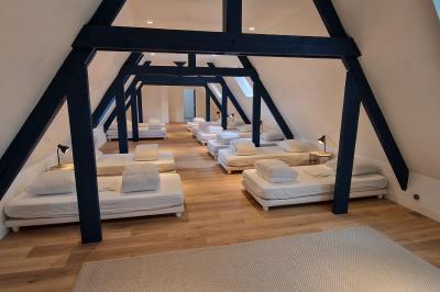 Salle spacieuse avec canapés, baby-foot, table de jeux et grandes fenêtres donnant sur un extérieur arboré.