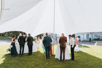 Salle spacieuse avec canapés, baby-foot, table de jeux et grandes fenêtres donnant sur un extérieur arboré.